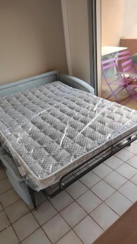 - un lit installé sur un sol carrelé dans l'établissement studio cabine quatre couchages classé 2 étoiles, à Bormes-les-Mimosas