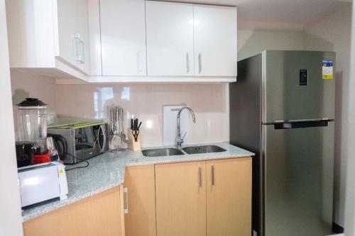 uma cozinha com armários brancos e um frigorífico verde em A2J Luxury Uptown 3BR Suite Near Uptown Mall em Manila