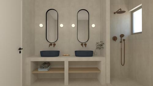 a bathroom with two sinks and two mirrors at Skiathos Ammos Luxury Apartments in Skiathos Town