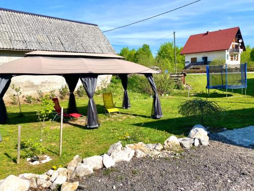 a large umbrella in a yard with a playground at Guest House Plitvice Waterfall in Plitvička Jezera