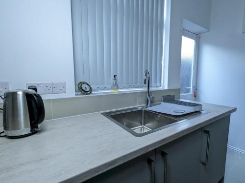 a kitchen counter with a sink and a window at Pass the Keys Spacious Comfortable 3 Bedroom House in Birmingham