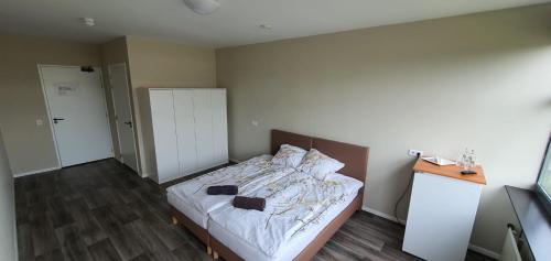 um quarto com uma cama com lençóis brancos e piso em madeira em Hiway Motel em Siebengewald