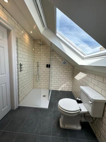 a bathroom with a toilet and a shower with a skylight at Rooms Above Sugar Boat in Helensburgh
