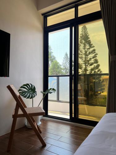 a bedroom with a chair and a window with a plant at 默森民宿 in Huxi