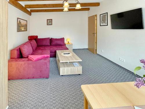 ein Wohnzimmer mit einem roten Sofa und einem Tisch in der Unterkunft Ferienwohnung Hibiskus in Lübbenau