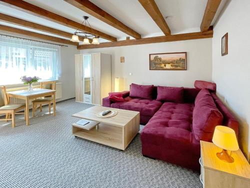 ein Wohnzimmer mit einem roten Sofa und einem Tisch in der Unterkunft Ferienwohnung Hibiskus in Lübbenau