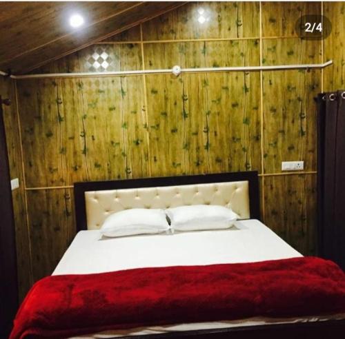 a bedroom with a white bed with a red blanket at Golden valley cottages, Chail in Chail