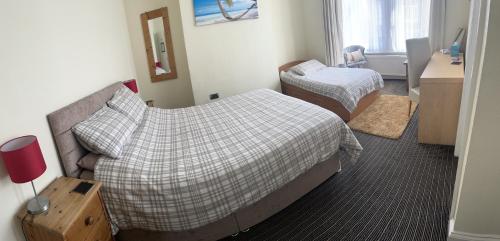 a bedroom with two beds and a desk and a window at The Swallow Hotel in Bridlington
