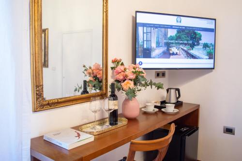 a desk with a mirror and a vase of flowers at Suite Nettuno Paestum in Paestum