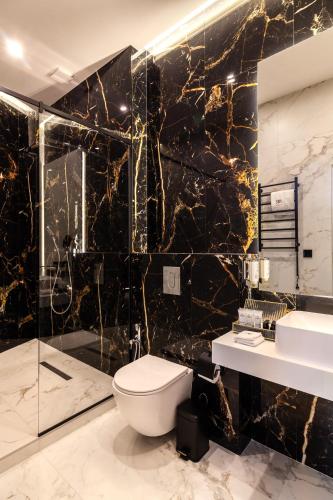 a black marble bathroom with a toilet and a sink at ARISTO Jacuzzi Hotel in Lviv