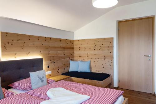 a bedroom with a bed and a wooden wall at Schererhof Dolomitenblick in Castelrotto