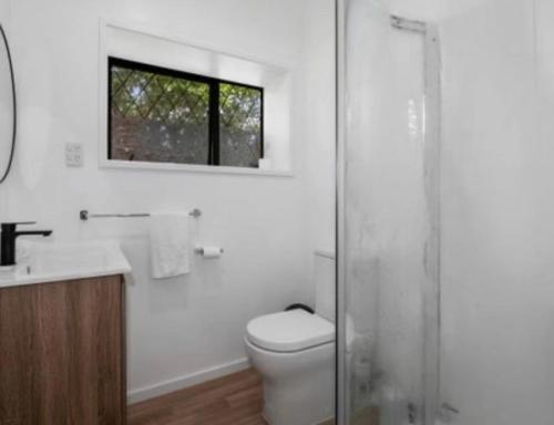 a bathroom with a toilet and a sink and a window at Young Woods Lodge in Rotorua