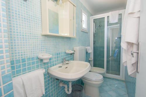 a blue tiled bathroom with a sink and a toilet at Lucia Maison in Ischia
