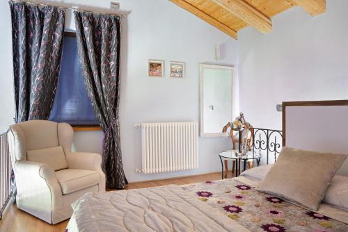 1 dormitorio con 1 cama, 1 silla y 1 ventana en La Corte di Langa Casa Ametista, en Albaretto Della Torre 