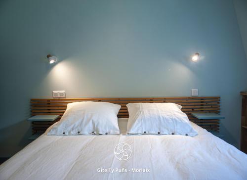 a bedroom with a bed with two pillows at Ty Puns - Gîte écoresponsable dans un espace verdoyant en centre-ville in Morlaix