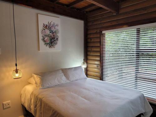 um quarto com uma cama branca e uma janela em Varswaterkloof Houthuis em Paarl