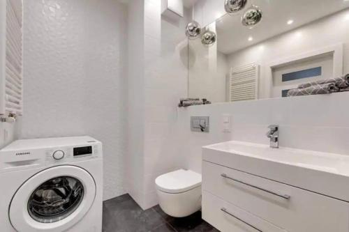 uma casa de banho branca com uma máquina de lavar roupa e um lavatório em Golden Apartments&Glamping-DG10 em Gdańsk