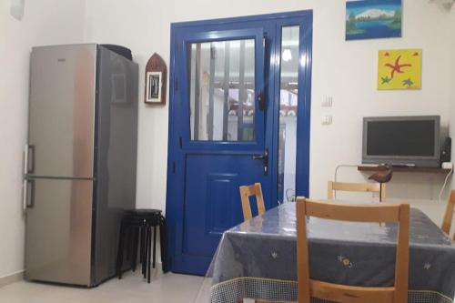 cocina con puerta azul, mesa y nevera en Lovely Vacation Home, en Poros