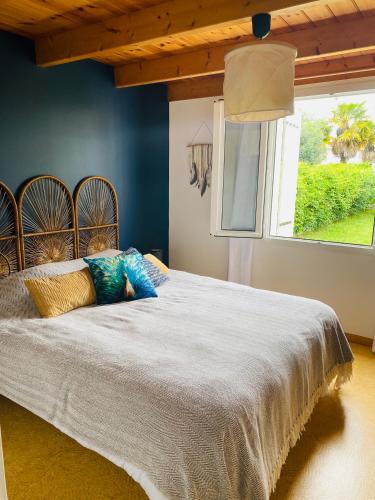 - une chambre avec un grand lit aux murs bleus et une fenêtre dans l'établissement La Fleur des Marais, au Château-dʼOléron