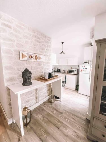 - une cuisine blanche avec une table et un mur en pierre dans l'établissement Havre de paix, jardin, place parking proche plage, à Montpellier