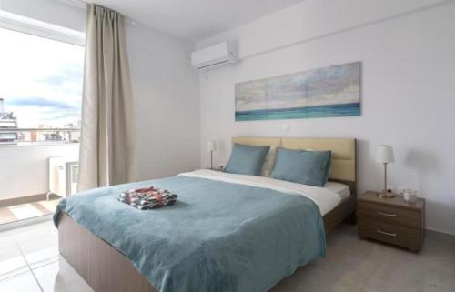 Schlafzimmer mit einem Bett mit blauer Bettwäsche und einem Fenster in der Unterkunft New spacious apartment located in Piraeus in Piräus