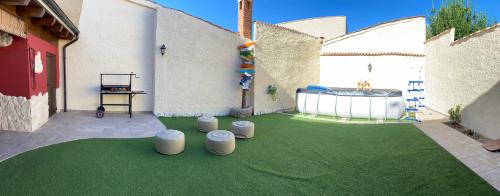 a backyard with a green yard with four stools at Casa Aurora in Sanchidrián