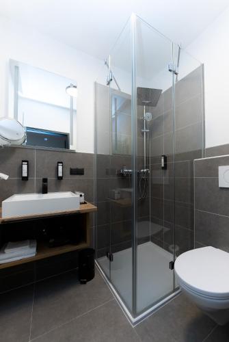 a bathroom with a shower and a sink and a toilet at Self-Check-in Hotel VinoQ Zistersdorf in Zistersdorf
