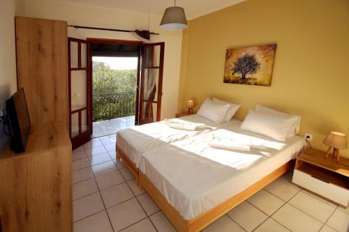ein Schlafzimmer mit einem großen weißen Bett und einem Balkon in der Unterkunft Green House!! in Sfakerá