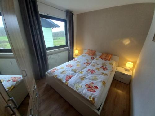 um pequeno quarto com uma cama e uma janela em Ferienwohnung Sophia em Nohfelden