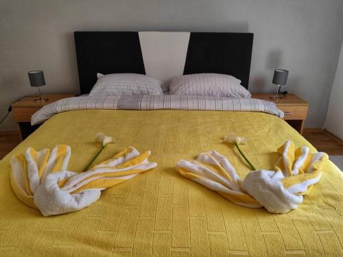 een bed met twee handdoeken erop met twee bloemen bij Apartman Lola in Višegrad