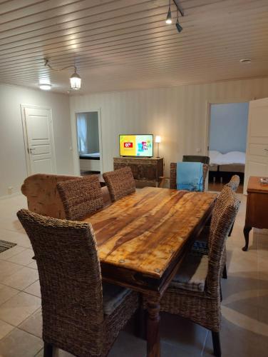 a wooden table with chairs and a living room at Nicolas apartment in Loimaa