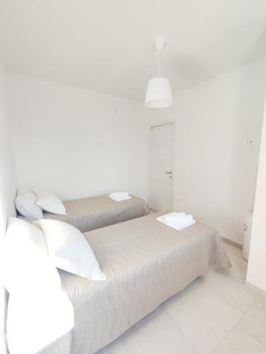 two beds in a room with white walls at Olive trees house in Torre Canne