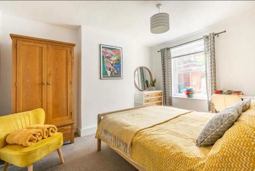 a bedroom with a bed and a yellow chair at Bradstone Garden Retreat in Folkestone
