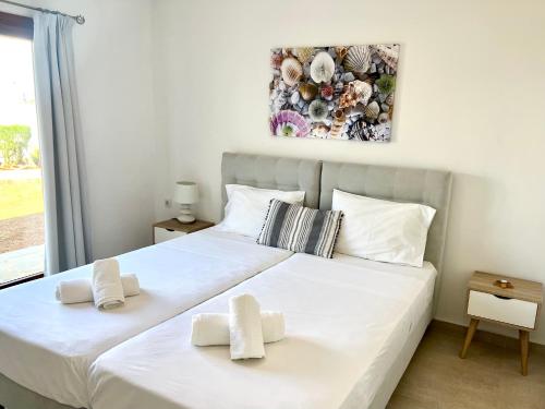 a bedroom with a large white bed with two towels at Kali Holiday Apartments in Stalida