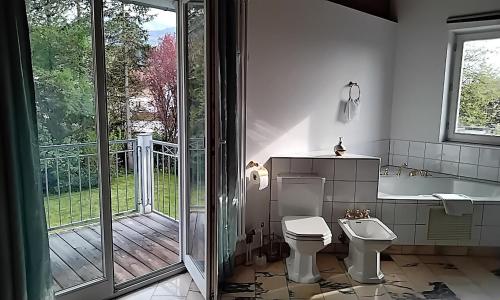 a bathroom with a tub and a toilet and a balcony at ciao-aschau Haus Beate in Frasdorf