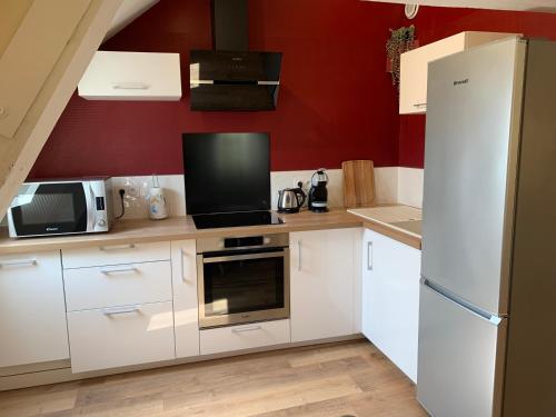 une cuisine avec des placards blancs et un mur rouge dans l'établissement APPARTMENT AU COEUR DU CENTRE HISTORIQUE 2 CH., à Bergerac