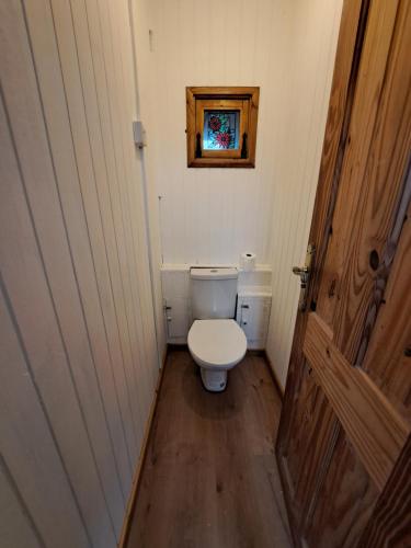 a small bathroom with a toilet and a wooden door at Beside the Seaside Chalet in Mablethorpe