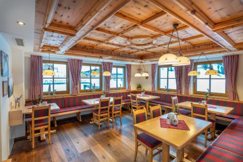 een restaurant met houten tafels en stoelen en ramen bij Apparthotel Kirchgasser in Obertauern