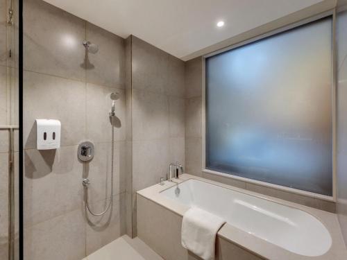 a bathroom with a shower and a tub and a large window at Amarpreet, Chhatrapati Sambhajinagar - AM Hotel Kollection in Aurangabad