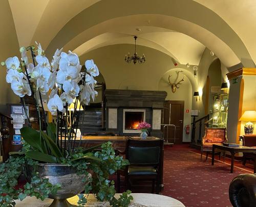 a lobby with a fireplace and a vase of flowers on a table at Zamek Podewils Krag in Krąg