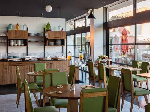 a restaurant with wooden tables and green chairs at New Hotel of Marseille - Vieux Port in Marseille