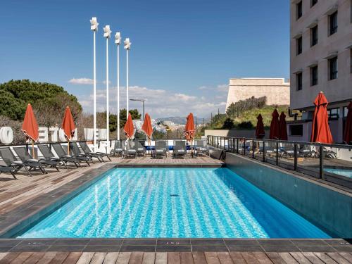 a swimming pool with chairs and umbrellas on a building at New Hotel of Marseille - Vieux Port in Marseille