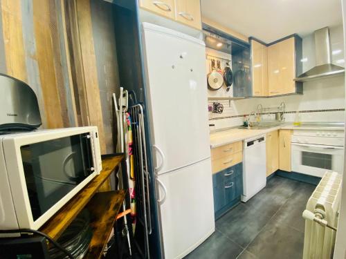 a kitchen with a white refrigerator and a tv at Raices in Robledondo