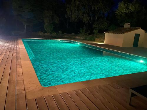 a swimming pool at night with a wooden deck at Magnifique villa avec piscine au coeur des vignes in Cogolin