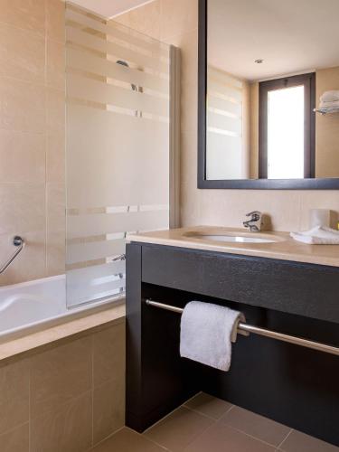 une salle de bain avec un lavabo, une baignoire et un miroir dans l'établissement New Hotel of Marseille - Vieux Port, à Marseille