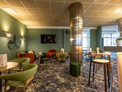 un restaurante con paredes verdes, mesas y sillas en Novotel Bourges en Bourges