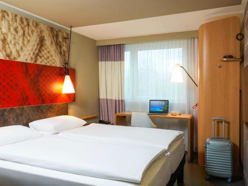 um quarto de hotel com uma cama e uma secretária com um computador em ibis Zurich Adliswil em Zürich