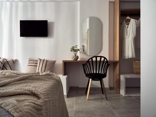 a bedroom with a bed and a chair and a mirror at Cassiopeia Rooms & Suites in Laganas