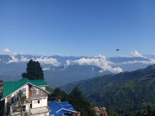 a building with a green roof with a view of mountains at Dew Drops Guest House in Darjeeling