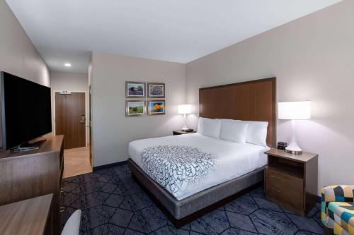 a hotel room with a bed and a flat screen tv at La Quinta Inn & Suites by Wyndham Round Rock near Kalahari in Round Rock